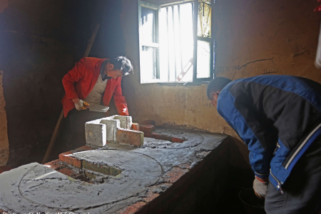 施工人员为一户家庭修建省柴炉灶。