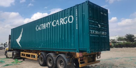 A large green Cathay Cargo truck parked on grass on a sunny day