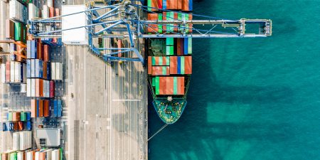 A container ship at a port alongside stacked containers