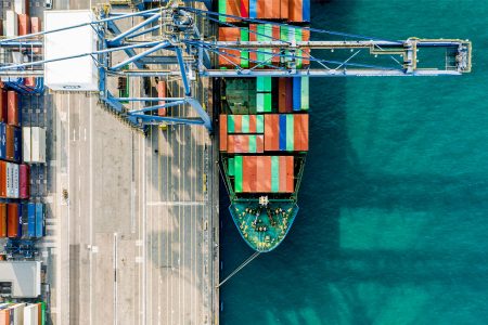 A container ship at a port alongside stacked containers