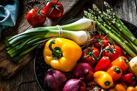 A pan full of fresh vegetables like bell peppers, onion and asparagus
