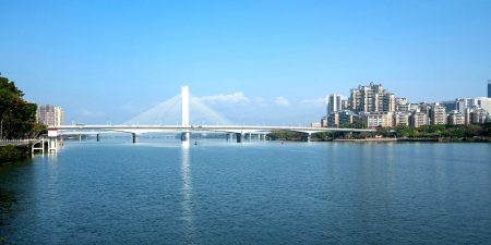 A bridge in Huizhou over water with buildings in the background 