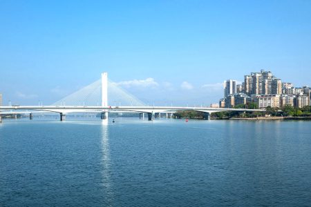 A bridge in Huizhou over water with buildings in the background 