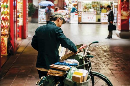 A bike courier with packages on a shopping street in China