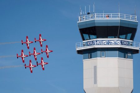 Small aircraft flying in formation near a control tower