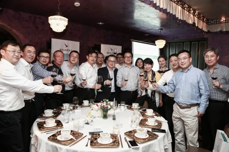 Dinner guests standing around table and toasting with wineglasses