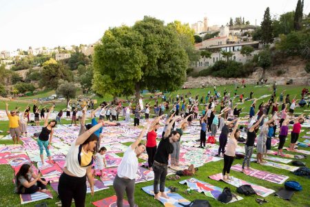 outdoor mass group yoga practice on grass in a public park