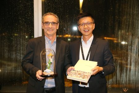 Ray Jewell holding gift (cartoon figurine) and Ronald Lam holding commemorative book