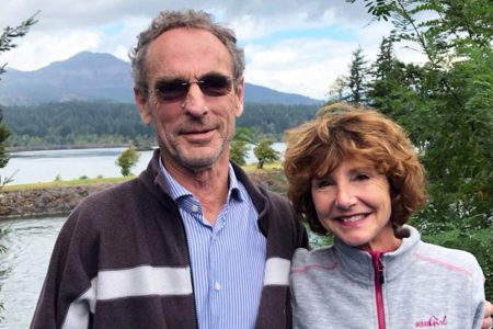 Ray Jewell with his wife Donatella outdoors with mountain and lake view