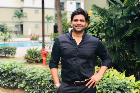 Siddhant Iyer standing near bush and swimming pool