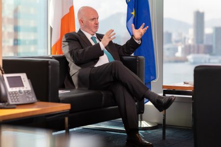 David Costello seated in an office with EU and Ireland flags behind sofa