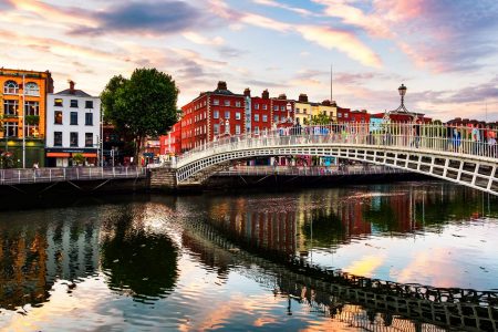 Ha'penny bridge over the river Liffey in Dublin at sunset, with pedestrians walking across