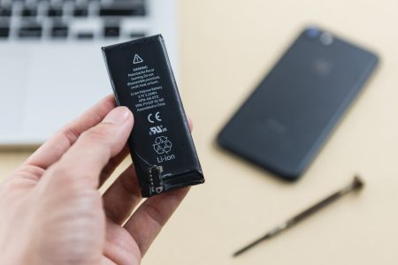 Lithium-ion battery held in hand, desktop in background