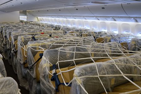 Boxes secured to wrapped passenger seats in aircraft cabin