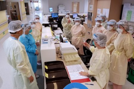 Healthcare workers wearing PPE at a hospital desk
