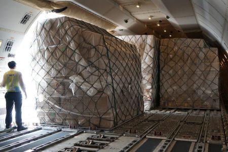 Crew standing inside Cargo aircraft near door as shipment is loaded in