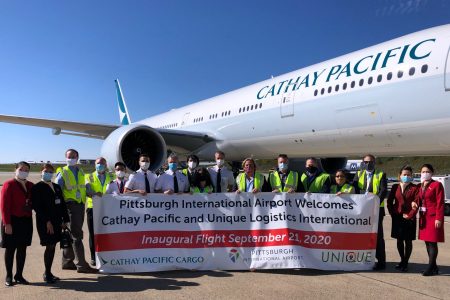 Cathay aircraft on tarmac and group posing for photo with banner
