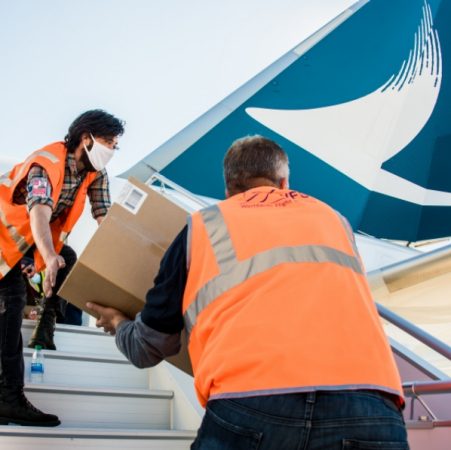 Ground crew passing box up stairs