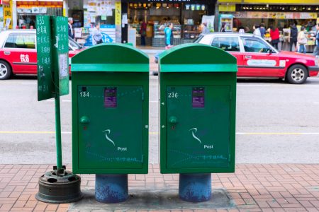Two postboxes with red taxis in the background