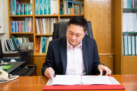 Patrick Lin at desk in office examining file
