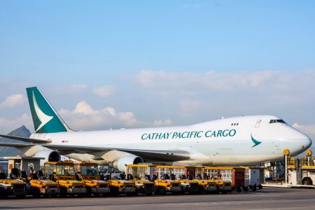 Cathay aircraft on tarmac with baggage tractors nearby