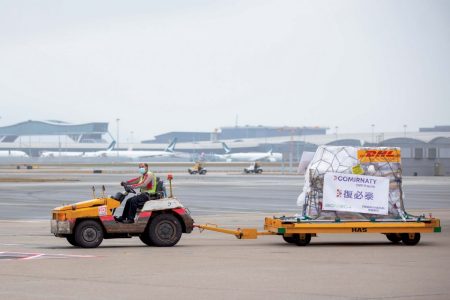Baggage tractor on tarmac with comirnaty labeled vaccine shipment
