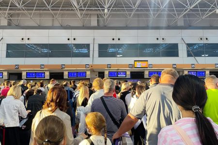 passengers lining up at crowded airport check-in counters