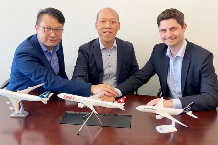Frank Yau, KennyLeung, Jorge Ahlborn put hands together on table with model aircraft