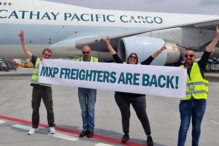 Cathay aircraft and team members on tarmac holding banner celebrating MXP return