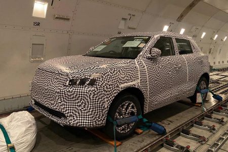 Electric car wrapped in camouflage secured to floor inside cargo aircraft