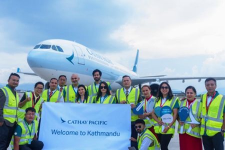 Cathay team in front of aircraft holding welcome banner