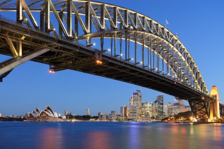 Sydney Harbour Bridge at dusk with Syndey Opera House and skyline visible in background