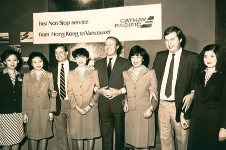 Black and white photo of Cathay executives at party with banner visible