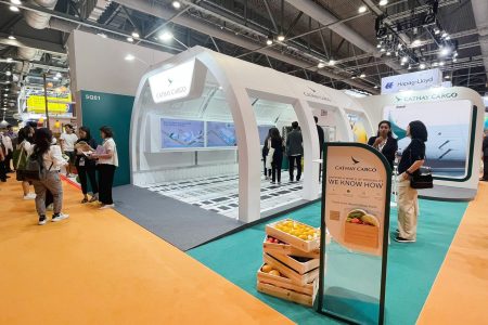 Visitors at Cathay Cargo exhibit at trade show, with a booth styled like aircraft fuselage