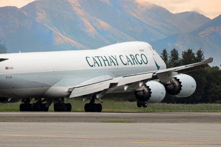 Cathay Cargo aircraft on runway, mountains in background