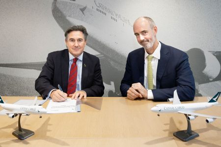 Tom Owen and Sean Dolan sitting at a table, signing a deal between Cathay Cargo and NorthLink Aviation, with model airplanes on the table