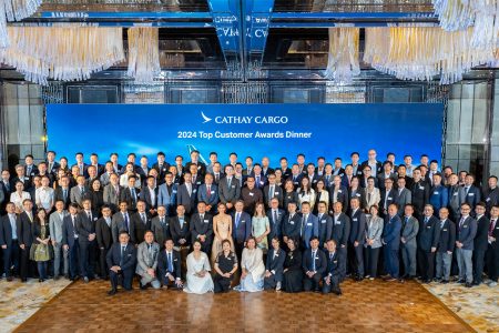A large group of people gather in front of a banner that says Cathay Cargo 2024 Top Customer Awards Dinner