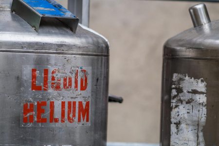 Two large metal containers, one labeled 'LIQUID HELIUM' with a blue top and visible wear.