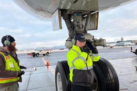 Licensed Aircraft Engineer Peter Chung checks in with the flight deck as the fueller looks on