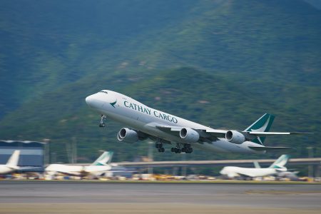 Cathay Cargo plane taking off with mountains in the background.