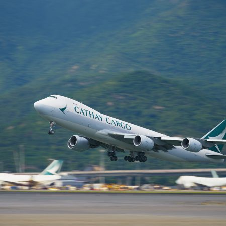 Cathay Cargo plane taking off with mountains in the background.