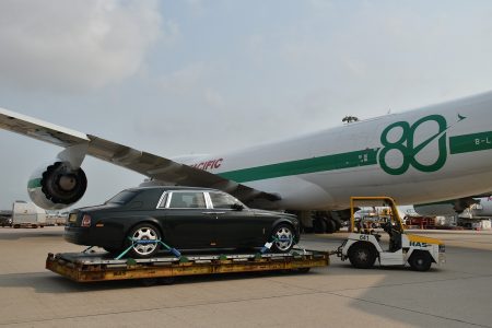 A Rolls-Royce Phantom on a dolly next to a special-livery Cathay Cargo Boeing 747 freighter at Hong Kong International Airport