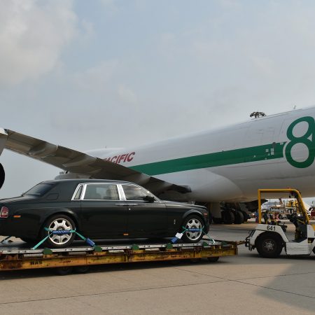 A Rolls-Royce Phantom on a dolly next to a special-livery Cathay Cargo Boeing 747 freighter at Hong Kong International Airport