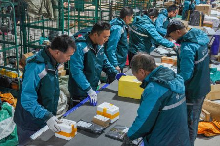 China Post personnel sort and scan parcels in a busy sorting office