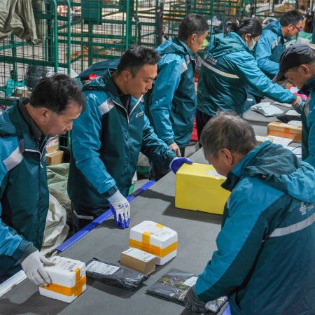 China Post personnel sort and scan parcels in a busy sorting office