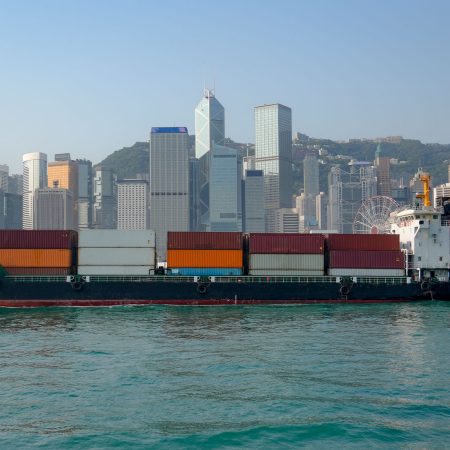 A river vessel with containers sails through Victoria Harbour in Hong Kong